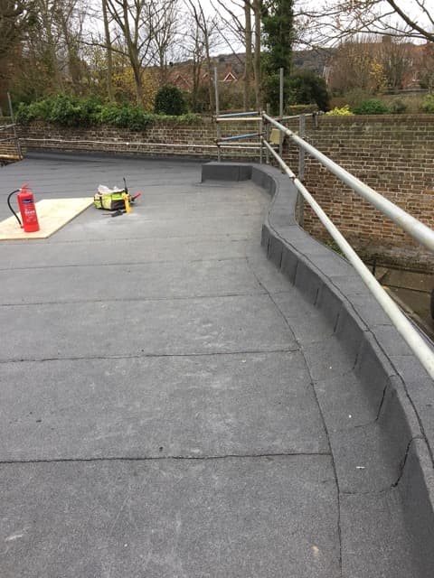 Grey felt flat roof with a curved parapet upstand